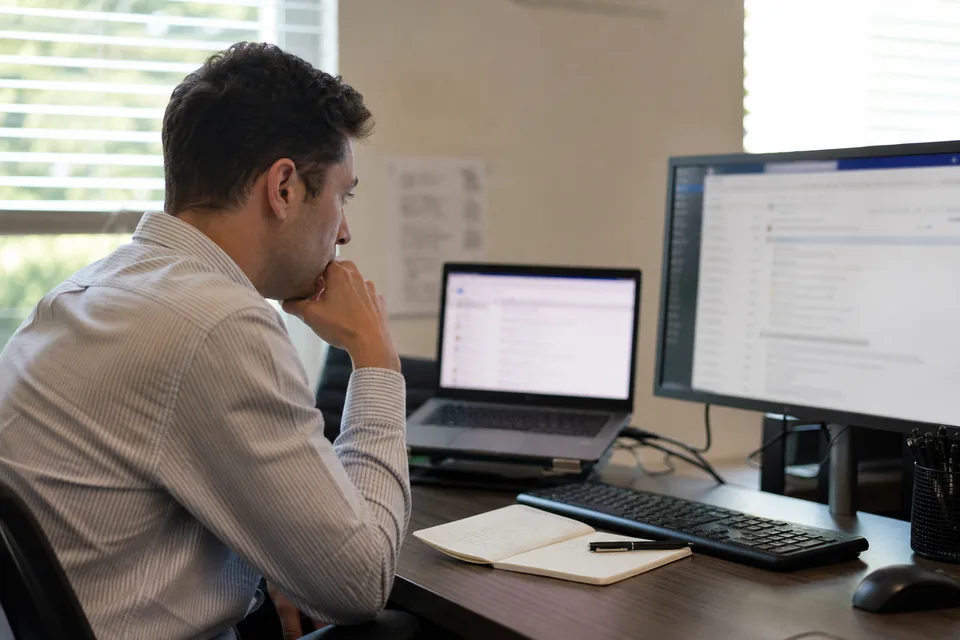 Sales rep at a desk reviewing a prospect list on a laptop next to an email inbox